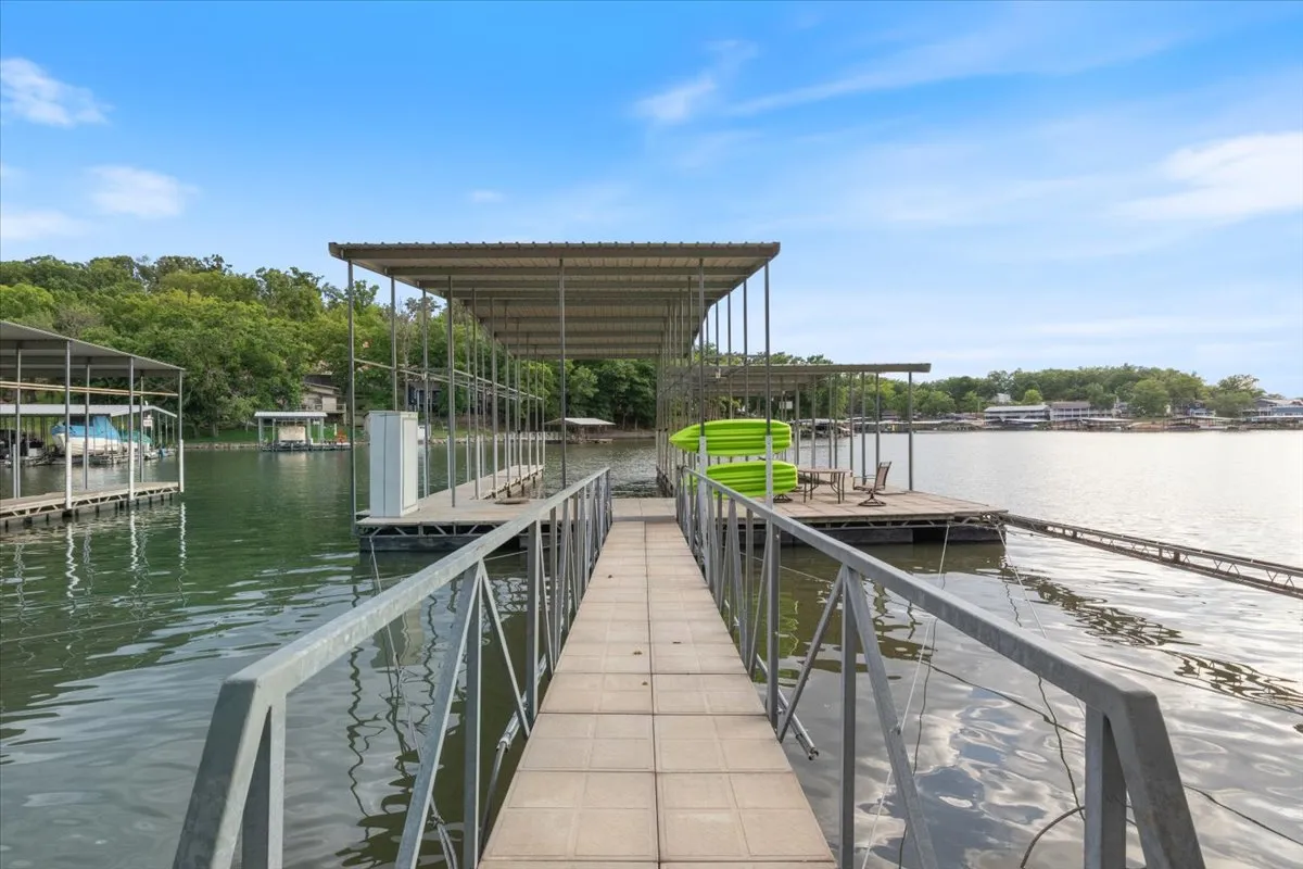 The photo features marina docks and a green waterslide extending into the lake, framed by verdant surroundings. Boats are visible, suggesting lively water activity, while the dock area hints at fun and relaxation on the water’s edge.