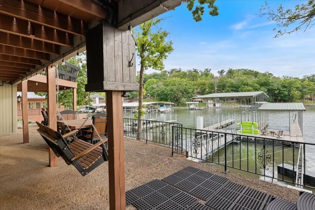 Swing chairs overlooking a sparkling waterfront and docks, surrounded by greenery. The scene invites guests to relax by the water, enjoy a morning coffee, or gather for sunset barbecues in a peaceful, welcoming environment.