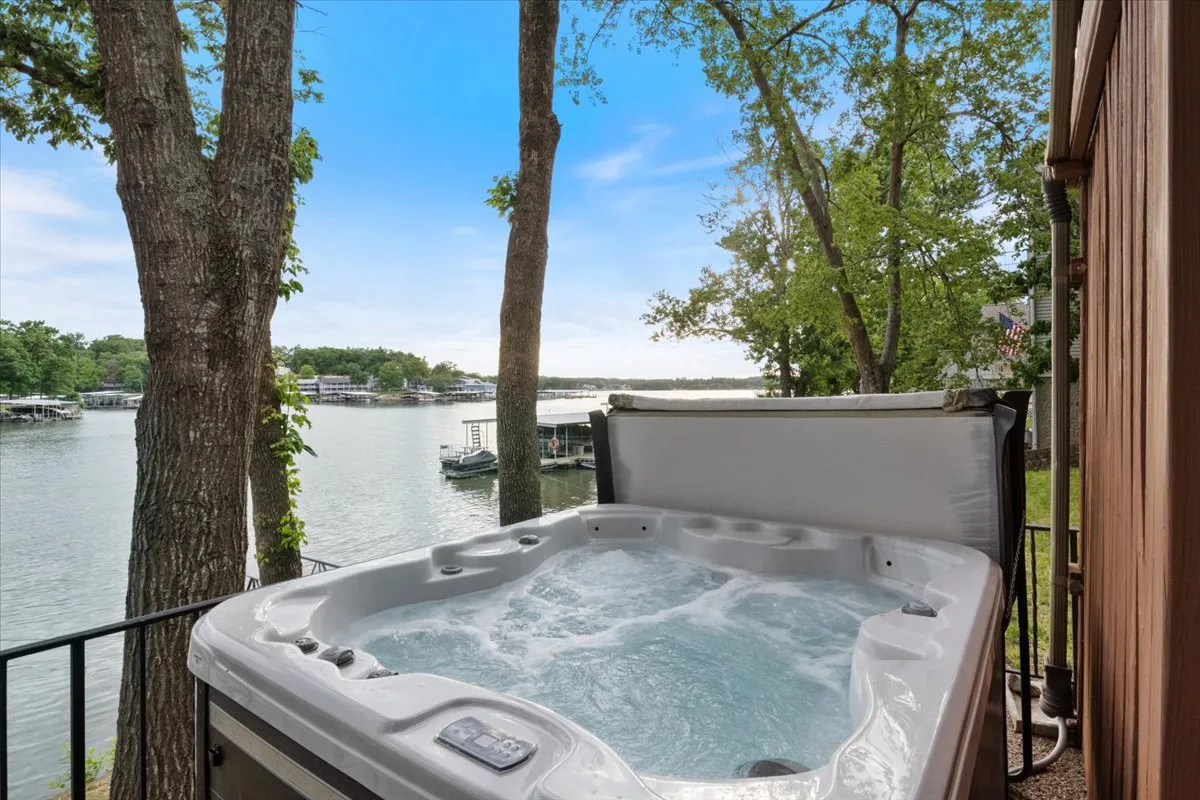 This image features a hot tub set on a deck with an expansive lake view framed by trees. The tranquil atmosphere is enhanced by the setting sun, inviting relaxation and social gatherings while enjoying the water scenery.