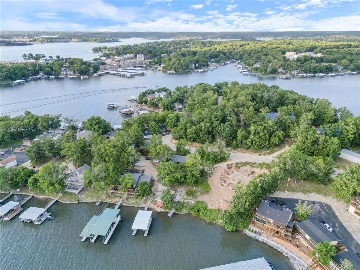 This image offers a sweeping view of the lake with marinas, boats, and lush greenery surrounding houses along the shoreline. The tranquil water is perfect for boating and fishing, while the scene captures the vibrant, accessible waterfront activity that defines Lake of the Ozarks.