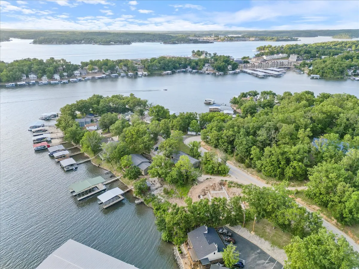 A panoramic exterior shot features the lake, marinas dotted with boats, surrounding trees, and riverside homes, evoking a sense of vibrant outdoor activity and community.