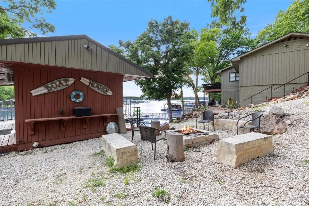 An inviting outdoor setup showcasing a boat house, fire pit with surrounding seating, and a beautiful view of the lake. The fire pit area is ready for evening gatherings, storytelling, or making s'mores after a day on the water.