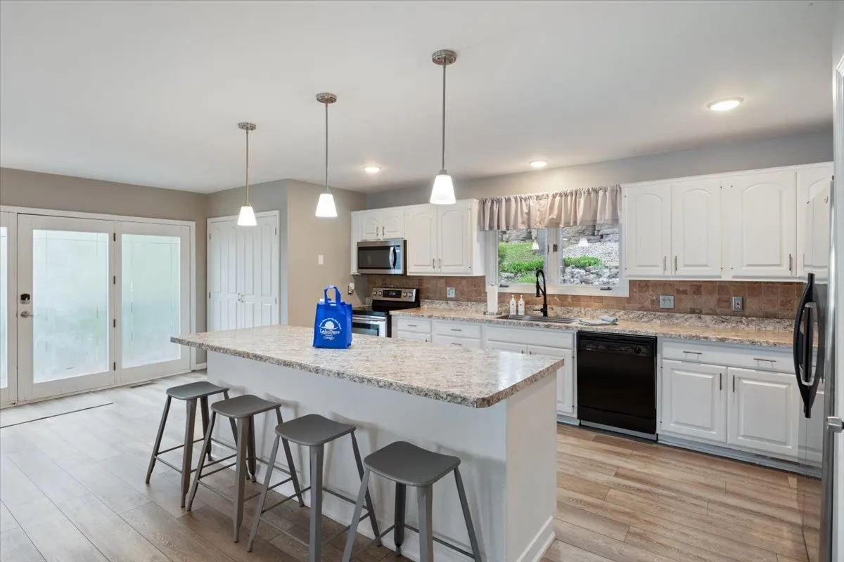 A warm, modern kitchen with a central island, stainless steel appliances, and a window framing the outdoor scenery. The arrangement is perfect for cooking together, casual dining, and sharing stories in a heart-of-the-home space.